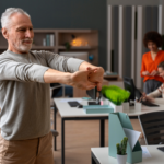 Uomo che esegue esercizi di stretching cervicale alla scrivania per la fisioterapia preventiva sul lavoro.