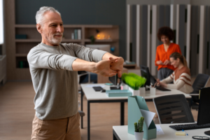 Uomo che esegue esercizi di stretching cervicale alla scrivania per la fisioterapia preventiva sul lavoro.